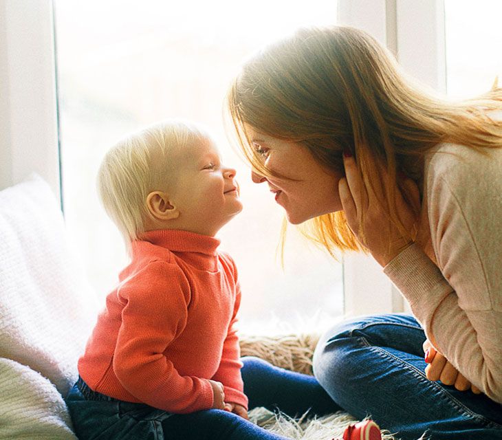A mother and her young child smiling at each other
